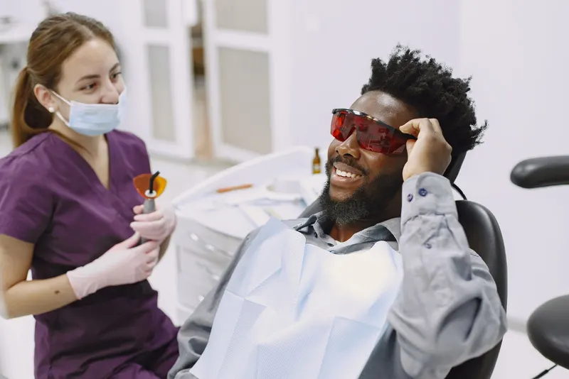 Lächelnder Patient mit Schutzbrille beim Bleaching